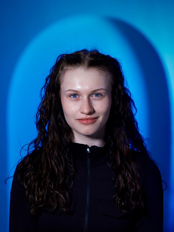 Anna Priester vor blauem Hintergrund